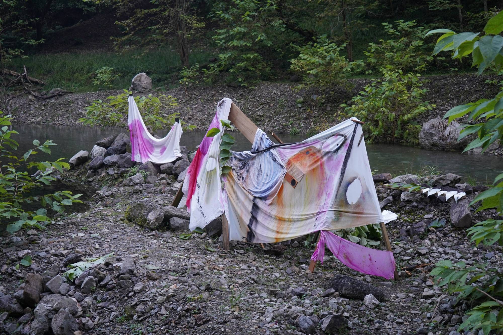 川原の木枠に掛けた彩色された布と、その奥の川